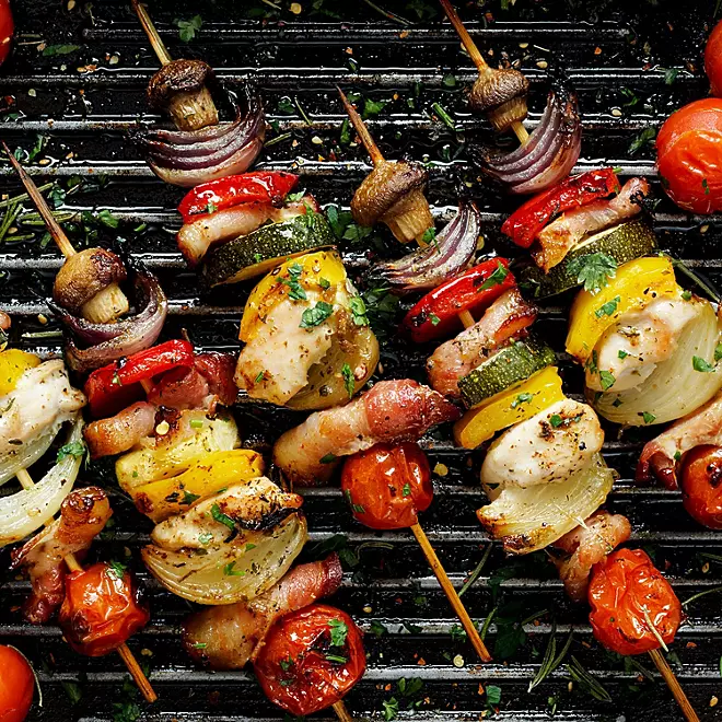 Char-grilled veggie skewers with peppers, onions, and zucchini on a wooden board